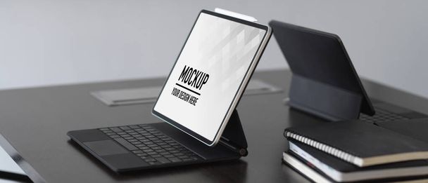 Seitenansicht von zwei digitalen Tablets und Notebooks auf dem Tisch im Besprechungsraum - Foto, Bild