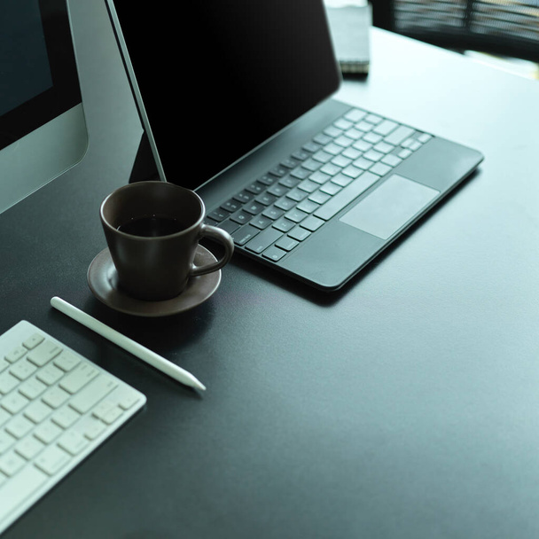 Vista lateral da mesa de escritório com teclado de computador, teclado de laptop, xícara de café e espaço de cópia  - Foto, Imagem