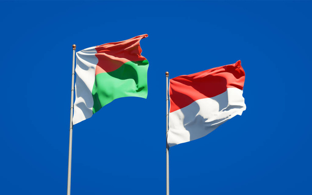 Hermosas banderas estatales nacionales de Madagascar e Indonesia juntas en el fondo del cielo. Concepto de obra de arte 3D.  - Foto, imagen