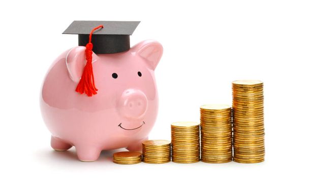 Hucha de cerdito en gorra de graduado cerca de pila de monedas. Ahorro para la educación. Precios de la educación superior - Foto, Imagen
