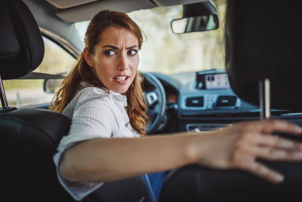 Aufnahme einer gestressten Geschäftsfrau, die während ihres morgendlichen Pendelns mit ihrem Auto im Stau steht. - Foto, Bild