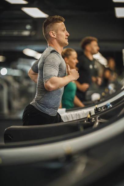 Shot of a young man jogging on a treadmill at the gym. - Zdjęcie, obraz