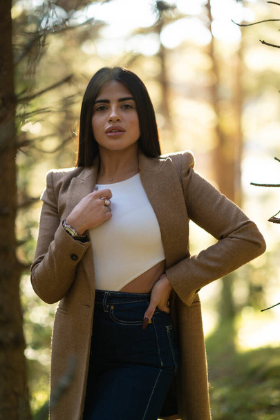 A selective focus shot  of a stylish brunette woman in a brown coat in a forest - autumn mood - Fotografie, Obrázek