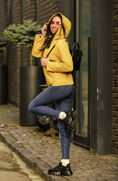 Outdoors lifestyle fashion portrait. walking on the autumn city. Wearing stylish bright outerwear. trendy girl in glasses. portrait of beautiful girl in autumn jacket. fashion model looking at camera - Foto, Imagen