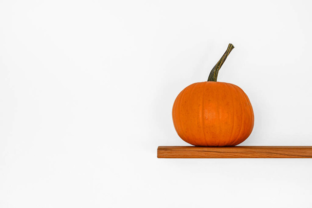 A pumpkin on a wooden shelf isolated on a white background - Fotó, kép