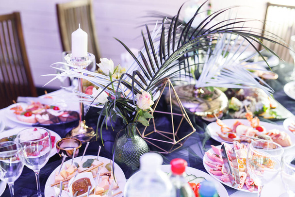 Primer plano de mesa festiva con copas de vino, comida y helecho fresco. Banquete de selebración en blanco y negro - Foto, imagen