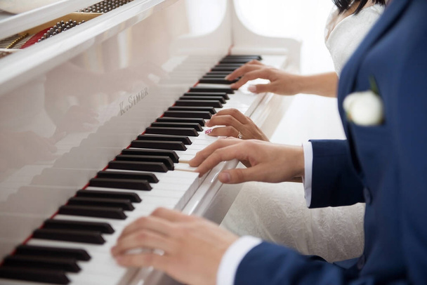 Gli sposi suonano il pianoforte in due mani. Le mani degli sposi sui tasti del pianoforte - Foto, immagini
