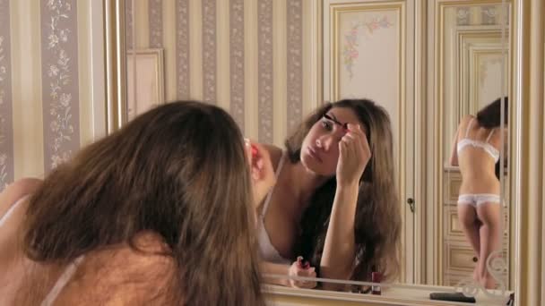 女の子は鏡の前にまつげを塗料します。 - 映像、動画