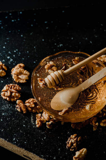 Hunaja lasi kulhoon saksanpähkinöitä ja puulusikoita - Valokuva, kuva
