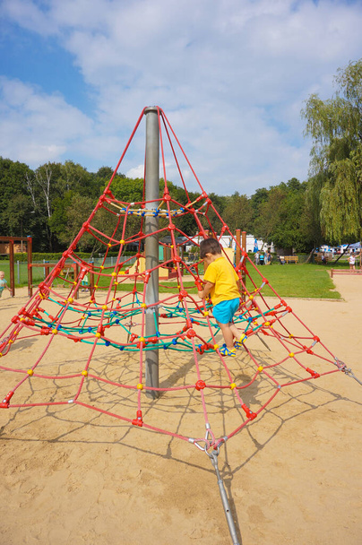 POZNAN, POLAND - Jun 10, 2020: Young boy climbing on a net equipment at a playground - Foto, immagini
