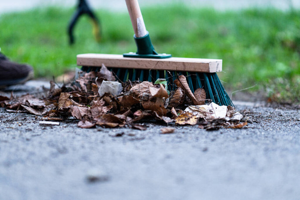 A closeup of a green street broom used in cleaning a pavement - 写真・画像