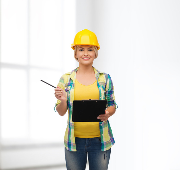 Smiling woman in helmet with clipboard - Photo, image