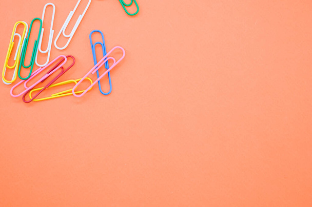 A closeup shot of colorful paper clips on an orange background - Zdjęcie, obraz