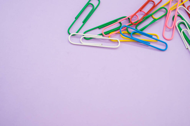A closeup shot of colorful paper clips on a purple background - Фото, изображение