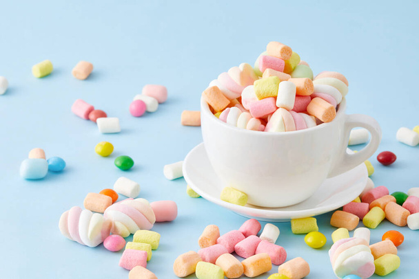 A top view closeup of a cup filled with colorful marshmallows isolated on a blue background - Fotografie, Obrázek