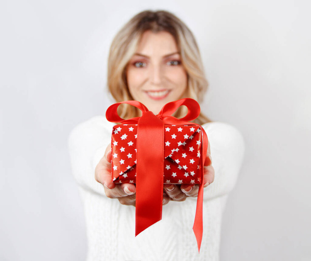 Улыбающаяся молодая женщина держит в руках подарок. селективный фокус - Фото, изображение