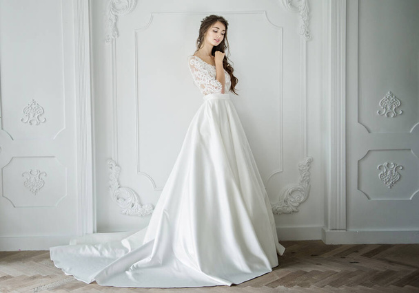 Portré egy fiatal menyasszony egy divatos esküvői ruha gyönyörű smink és frizura, stúdió fotó beltérben. Fiatal, vonzó modell - Fotó, kép
