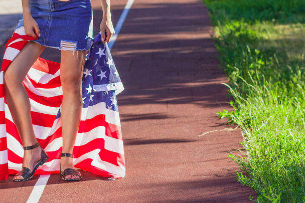 Woman with a flag of United States of America in the hands, outdoors, soft focus background - Foto, afbeelding