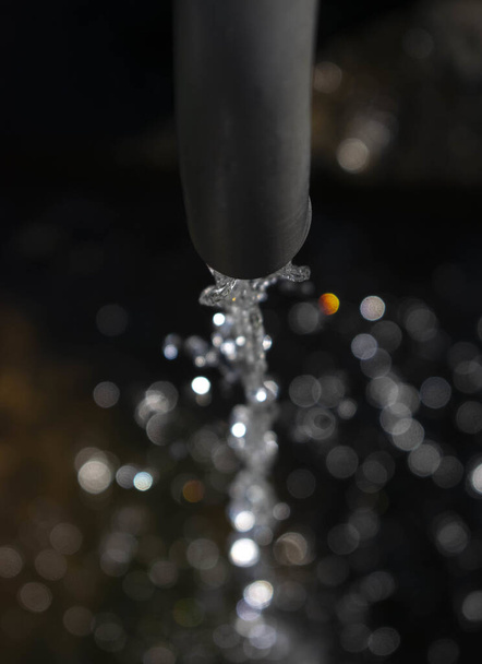 A vertical shot of a small water jet getting out of a faucet - 写真・画像