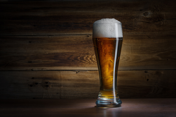 beer glass on a wooden background - Foto, afbeelding