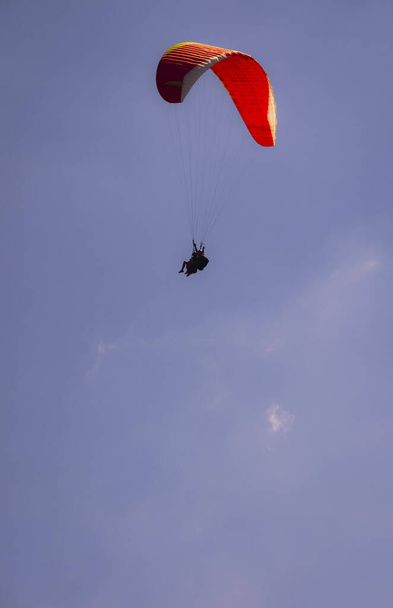 Um tiro vertical de uma pessoa parasailing alto no céu - Foto, Imagem