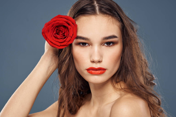 mujer con una rosa en sus manos hombros desnudos maquillaje de noche labios rojos - Foto, imagen