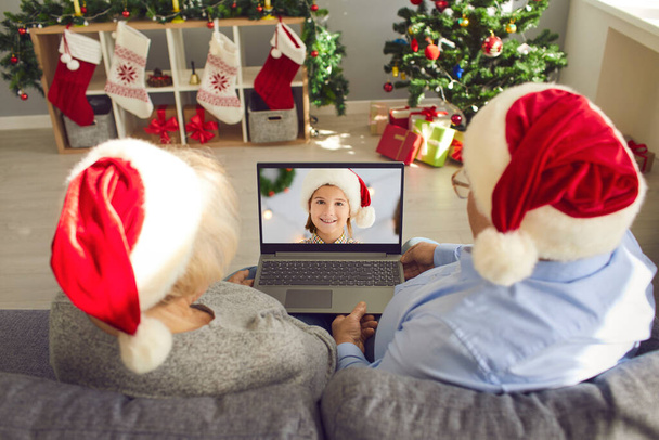 Grandparents in Santa caps video calling their little granddaughter on Christmas Day - Photo, image