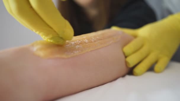 Kozmetikus gyantáztatja a nők lábát a szépségszalonban. A lábak nyírására vonatkozó eljárás. - Felvétel, videó