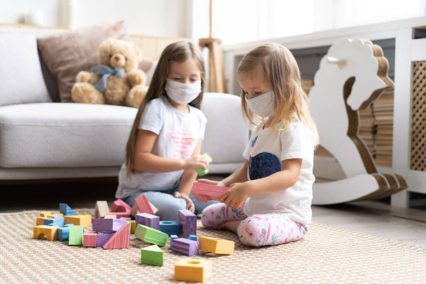 Kids children wearing mask for protect Covid-19, playing block toys in playroom. - Foto, Bild