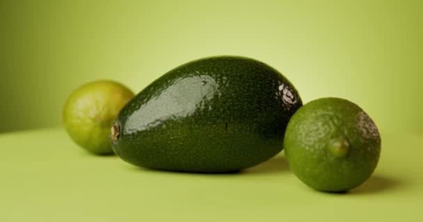 roterende verse avocado en limoen op groene achtergrond - Video