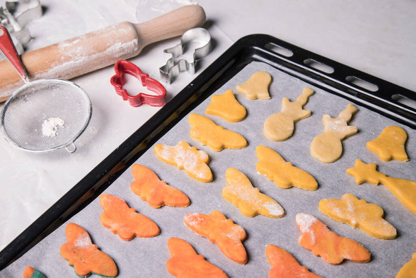 Домашнє печиво у вигляді метеликів, дзвонів та сніговиків перед випічкою на випічці, вирізанням форм та прокатним штифтом на білій скатертині. Близько. Горизонтальна орієнтація
 - Фото, зображення