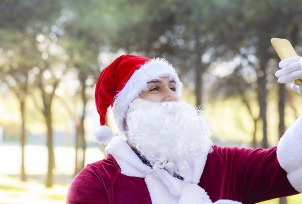 Der Weihnachtsmann fotografiert mit seinem Handy im Wald - Foto, Bild