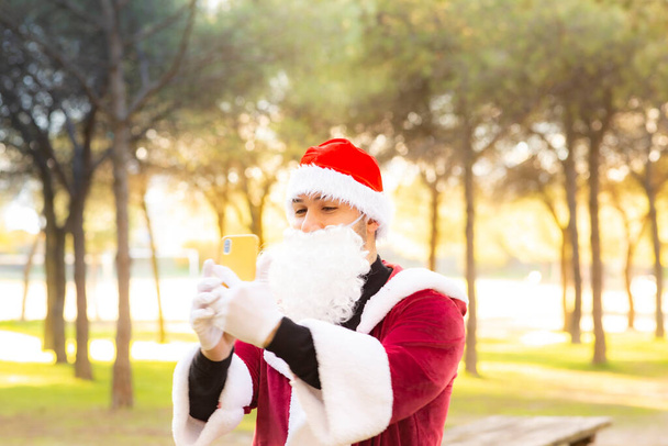 Babbo Natale scatta foto con il suo cellulare nella foresta - Foto, immagini