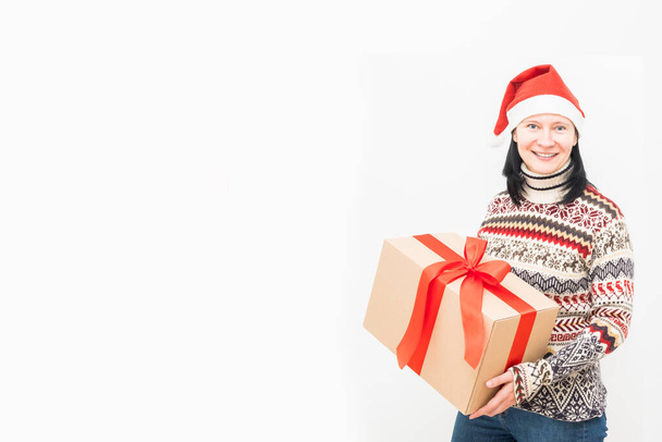 Woman courier in santa hat and christmas sweater holding gift on light background. - Foto, Imagen