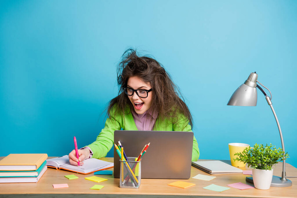 Портрет божевільного коричневого брудного волосся дівчина сидить на столі робота віддаленого запису копіювальної книги ізольовано на синьому кольорі фоні
 - Фото, зображення