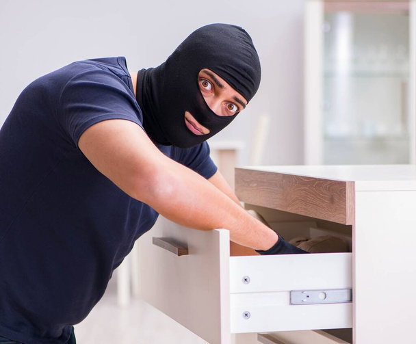 Robber wearing balaclava stealing valuable things - Фото, зображення