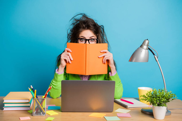 Ritratto di stupito marrone disordinato ragazza capelli sedersi scrivania chiudere copertina libro faccia isolato blu colore sfondo - Foto, immagini