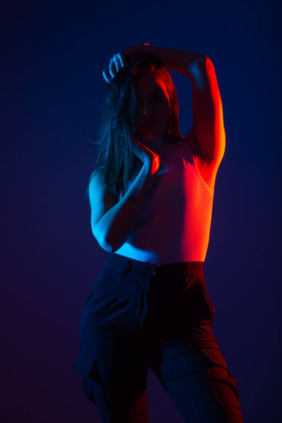 Female model posing in studio with red and blue colors at high contrast. - Фото, изображение