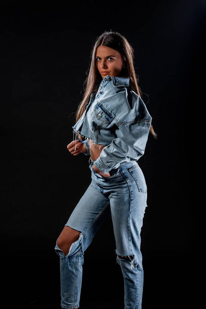 Elegante mujer joven con pantalones de mezclilla azul y chaqueta de jean recortada - Foto, imagen