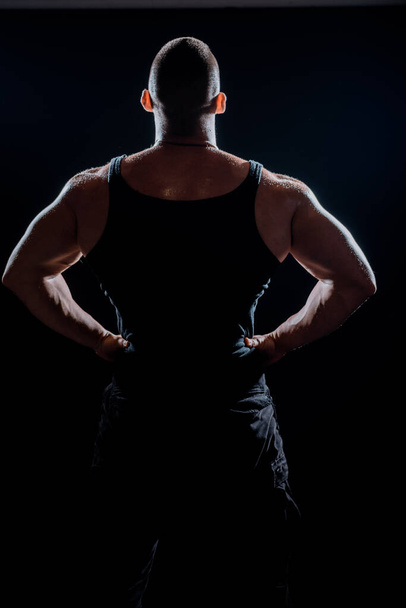 Подходит человек на черном фоне. Подходящий спортсмен показывает мышцы. Сильный спортсмен с крепким телом - Фото, изображение