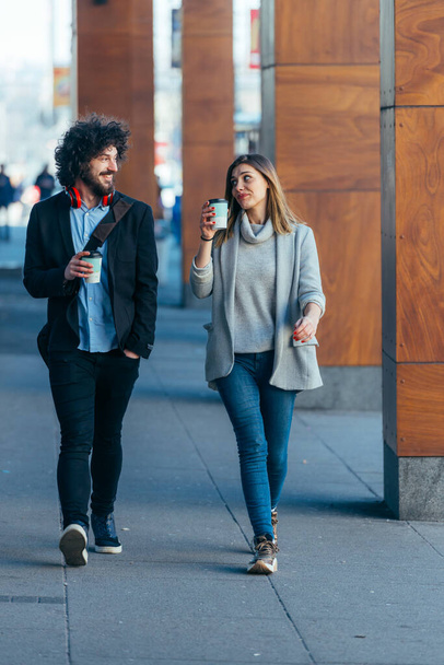 Üzleti pár (kollégák) séta a futurisztikus modern állomás (repülőtér), miközben kávéznak és beszélgetnek egymással. - Fotó, kép