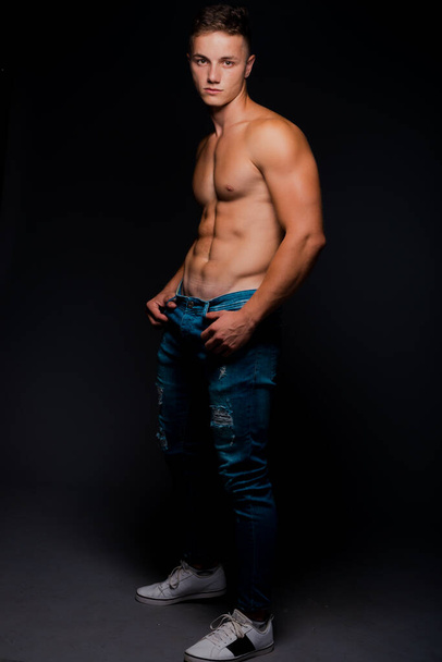 Portrait of a handsome male model posing in trendy blue denim jeans - Photo, Image