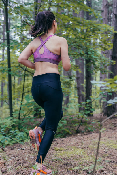 Imagen de la espalda de una joven deportista corriendo por el bosque - Foto, imagen