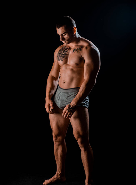 Sport en training. Man met gespierd lichaam. Atletische bodybuilder pose - Foto, afbeelding