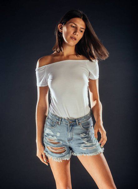 Современная женщина в порванных джинсовых шортах и белом топе - Фото, изображение