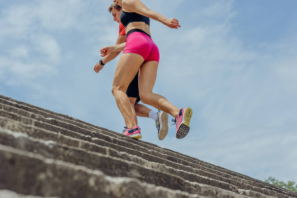 Close up and low below angle view photo of athletes legs running up concrete stairs - Photo, Image