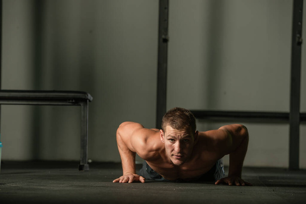 Strong male athlete doing push-ups indoors. Close up perspective, healthy lifestyle, fatless body. - Fotó, kép