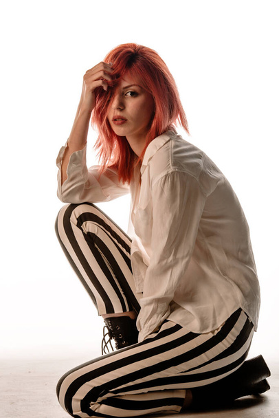 Portrait of a beautiful female model posing in trendy stripe pants and white long shirt - Photo, Image