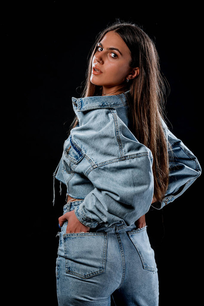 Стильная молодая женщина в джинсовых брюках и обрезанной джинсовой куртке - Фото, изображение