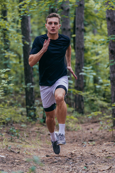 Ormanda koşan yakışıklı bir koşucunun yakın çekimi. - Fotoğraf, Görsel
